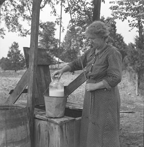 Woman putting milk in well buckett - Aunt Minnie